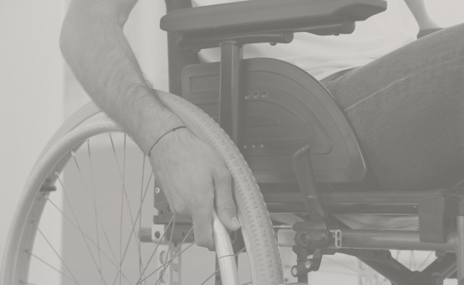 Closeup of a man’s hand on the wheel of his wheelchair
